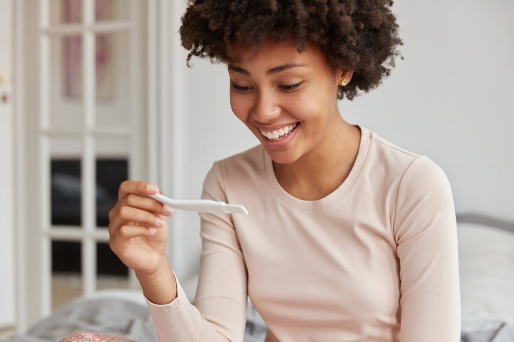 Femme heureuse qui tient un test de grossesse