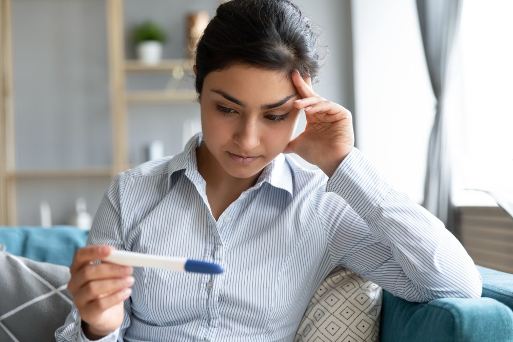 Femme inquiète qui regarde un test de grossesse