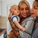 Portrait de deux jeunes femmes couple lesbien souriant avec leur bébé illustrant les droits parent social dans famille homoparentale