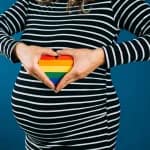 Femme enceinte tenant un cœur arc-en-ciel sur son ventre symbolisant la GPA en Europe pour couples LGBT