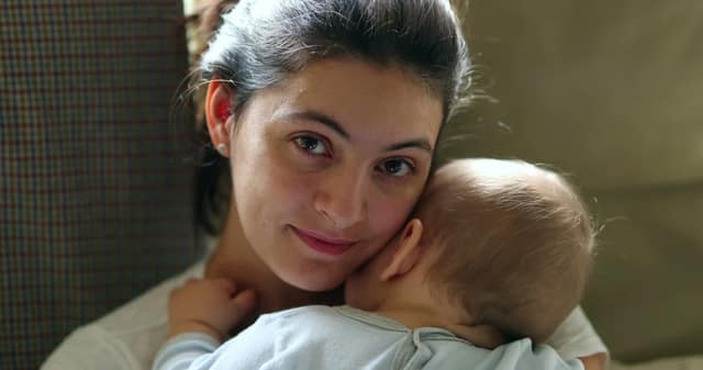 maman solo tenant son bébé dans les bras à la maison