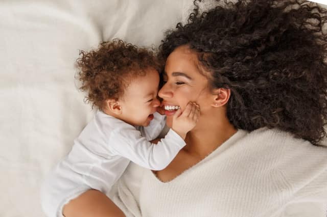Femme célibataire seule avec son bébé dans un lit illustrant le choix d'avoir un enfant célibataire