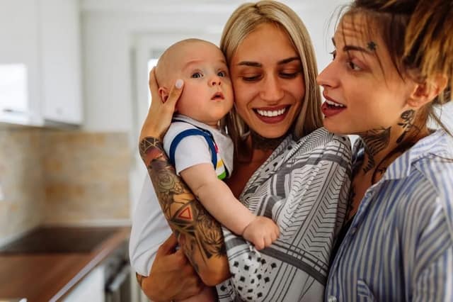 Portrait de deux jeunes femmes couple lesbien souriant avec leur bébé illustrant les droits parent social dans famille homoparentale