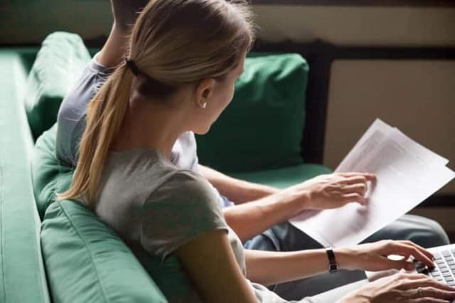 Couple lisant un contrat sur un canapé illustrant le consentement PMA.