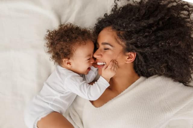 Femme célibataire seule avec son bébé dans un lit illustrant le choix d'avoir un enfant célibataire