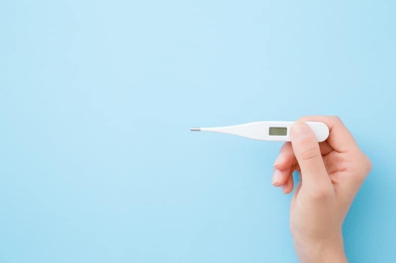 une main tenant thermomètre numérique