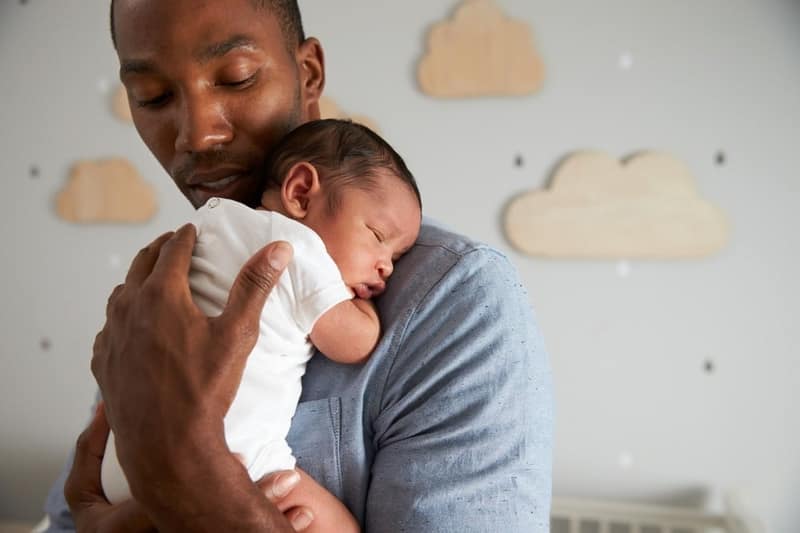Père qui tient son bébé qui dort dans les bras