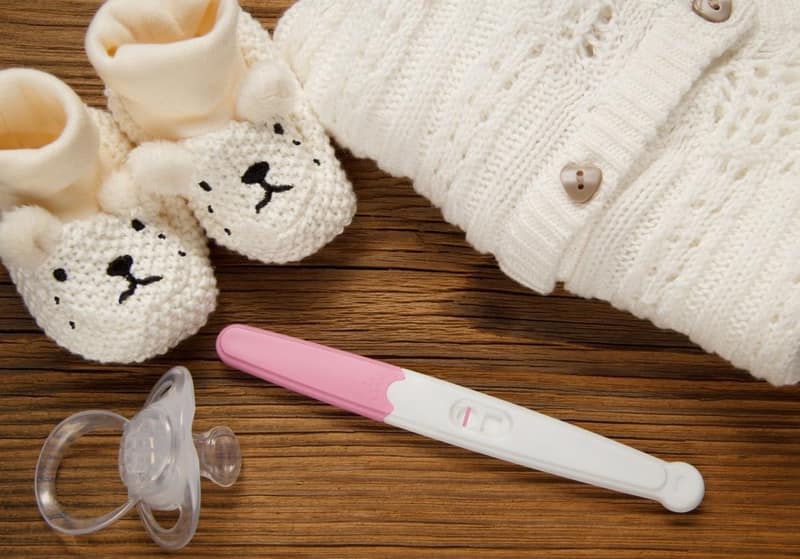 Test de grossesse avec des affaires de bébé